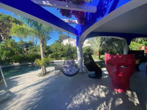 a porch with swings and a black dog sitting under an umbrella at Villa Karolina in Quarteira