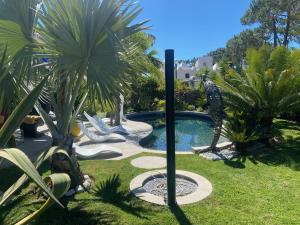a pool in a yard with palm trees and a man statue at Villa Karolina in Quarteira