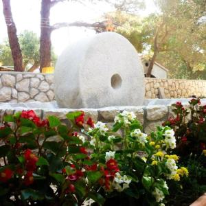 a stone bird bath in a garden with flowers at room MLIN 1 in Lun +4 photos