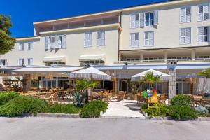 an exterior view of a hotel with tables and chairs at Hotel Adria in Malinska