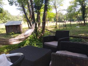 a hammock in a field with chairs and a table at tente type yourth dans les bois in Saint-Paulet-de-Caisson