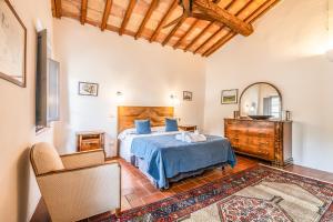 a bedroom with a bed and a chair and a mirror at Tenuta della Selva - Castellaccio 7 in Murlo