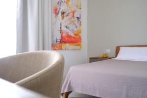 a bedroom with a bed and a chair and a painting at Nafura in Raffadali