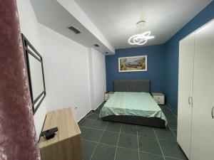 a bedroom with a bed and a blue wall at Dua Apartament in Kashari