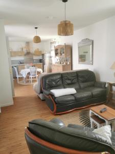a living room with a black leather couch and a table at La douce Campagne in Flavigny-le-Grand-et-Beaurain