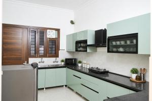 a kitchen with white cabinets and a clock on the wall at Noor Villa Mohali in Lāndrān