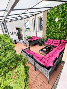 an outdoor patio with pink cushioned furniture and plants at Aparthotel - Stadtvilla Premium in Schweinfurt