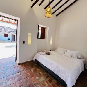 a bedroom with a large white bed and a large window at Casa de ejercicios zaxue colonial in Zapatoca