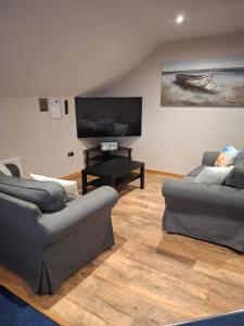 a living room with two couches and a flat screen tv at Reubens Loft for 1 to 6 person Family 4 miles outside Portrush Bushmills Coleraine Ballymoney in Bushmills