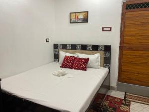 a bed with red pillows on it in a room at Govind Atithi grah in Ayodhya