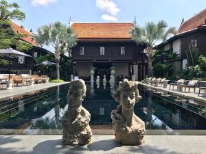 two statues sitting in front of a swimming pool at Villa Mahabhirom - SHA Plus in Chiang Mai