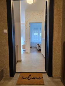 a hallway with a door to a room with a welcome mat at Gold Apartman in Pančevo