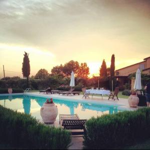 a swimming pool with chairs and umbrellas in a yard at La Cascina nel Roseto in Rigutino