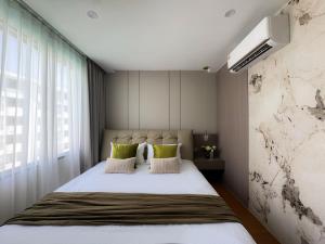 a bedroom with a large bed with green pillows at Stylish Pool View 1BDR Apartment Bang Tao in Ban Thalat Choeng Thale