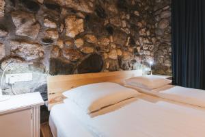 a bedroom with two beds and a stone wall at Sobe Lotrist in Radovljica