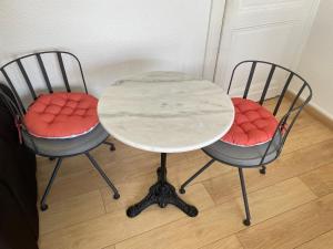 two chairs with a white table and a table and two chairs with red seats at Grande Chambre avec parking possible en supplément, BORDEAUX BASTIDE in Bordeaux +10 photos