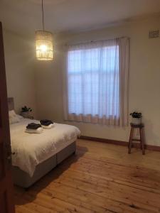 a bedroom with a bed and a large window at Muizenberg Surfers Lodge in Muizenberg