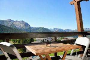 a wooden table and chairs on a balcony with mountains at Hostdomus - Royal View in Sestriere