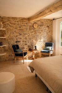 two chairs and a bed in a room with a stone wall at Le Mas des Chènes in Taradeau +35 photos