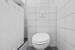 a bathroom with a white toilet and a white tile wall at City Residence - Sankt Pölten in Sankt Pölten +12 photos