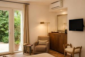 a living room with a tv and a chair and a window at Le Mas des Chènes in Taradeau