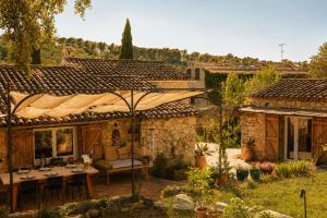a house with a table and an umbrella in the yard at Le Mas des Chènes in Taradeau
