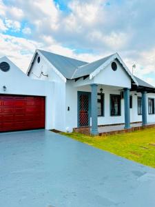 a white house with a red garage at The Private Place in eMalahleni
