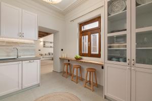 a kitchen with white cabinets and bar stools at Archontiko Residence in Koskinou