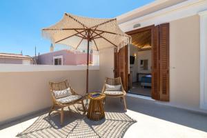 two chairs and a table with an umbrella on a balcony at Archontiko Residence in Koskinou