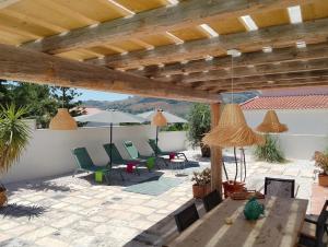 a patio with chairs and a table under a wooden pergola at LE SORELLE Sea front -villa whit private pool in Scopello