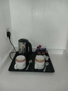 two coffee cups on a stove with a coffee maker at Le Maitre in Southport