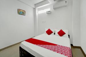 a white room with a bed with red pillows at Hotel O Radha Krishna Family Hotel in Naubatpur