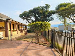 a fence in front of a building with trees at The Museum in Sabie