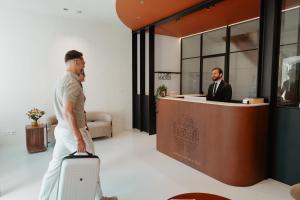 a man pulling a suitcase in front of a counter at Château du Pont d'Oye in Habay-la-Neuve