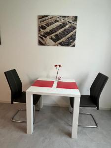 a white table with two chairs and a vase on it at Conny's Ferienwohnung in Bietigheim-Bissingen