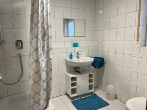 a white bathroom with a sink and a shower at Conny's Ferienwohnung in Bietigheim-Bissingen