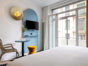 a bedroom with a bed and a tv and a window at Mercure Annecy Centre in Annecy