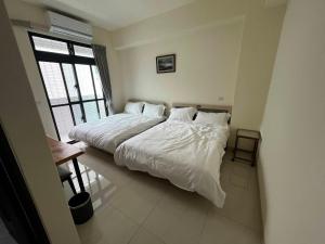 a bedroom with a bed with white sheets and a window at Green Home in Yuli