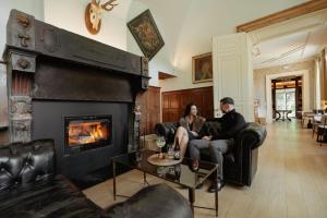 a man and woman sitting in a living room with a fireplace at Château du Pont d'Oye in Habay-la-Neuve
