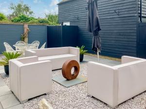 a patio with a white couch and an umbrella at Sea Scape in Whitstable