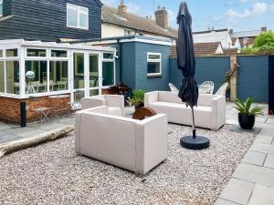 a patio with white couches and an umbrella at Sea Scape in Whitstable