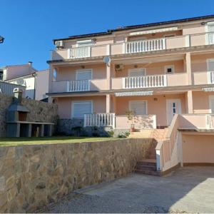 a large apartment building with a stone wall at Apartmani Azik in Lopar