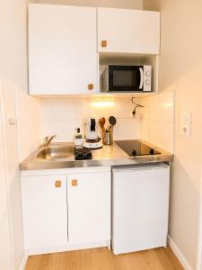 a kitchen with white cabinets and a sink and a microwave at Studio Sunshine Saint-Omer Centre in Saint-Omer +7 photos