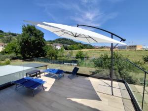 a patio with blue chairs and a white umbrella at Appartamento Cataleya in Cuccurano +6 photos