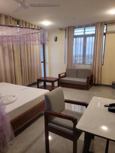 a room with two beds and a chair and a couch at Moveck Inn in Dar es Salaam