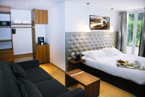 um quarto de hotel com uma cama e um sofá em Le Pré du Moulin - Maison Alonso - Hôtel & Restaurant em Sérignan-du-Comtat
