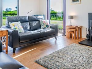 a living room with a leather couch and a fireplace at The Longhouse At Threave in Castle Douglas