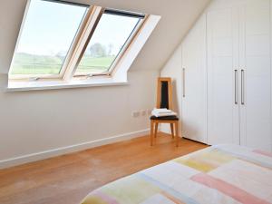 a bedroom with a window and a bed and a chair at The Longhouse At Threave in Castle Douglas