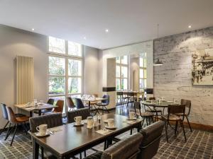 a restaurant with tables and chairs and a brick wall at Mercure Hotel & Residenz Berlin Checkpoint Charlie in Berlin