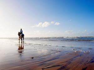 osoba jadąca konno po plaży w obiekcie Pullman Mazagan Royal Golf & Spa w mieście Al-Dżadida